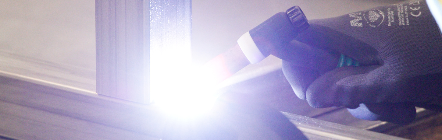 Fabrication technician welding precision metal components at Herman Goldner Co., Inc. facility in Philadelphia.