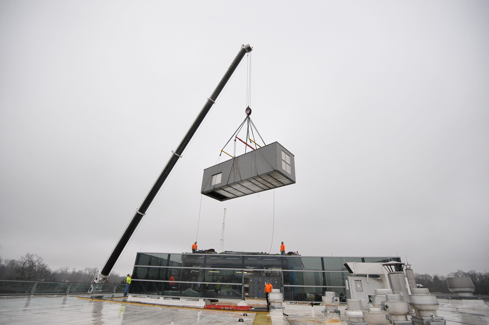 Crane lifting large mechanical rooftop unit installed by Herman Goldner Co., Inc. as part of a commercial HVAC system upgrade in Philadelphia.