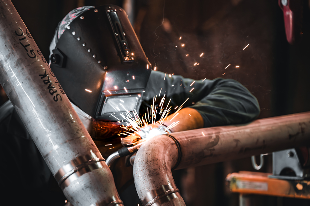 Fabrication specialist assembling prefabricated steel piping systems at Herman Goldner Co., Inc. workshop.