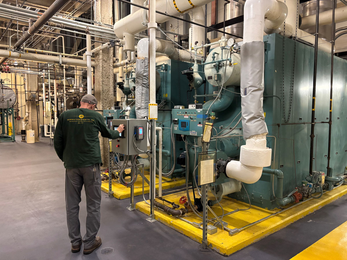 Herman Goldner Co., Inc. technician inspecting mechanical equipment and performing preventive maintenance on commercial HVAC systems.