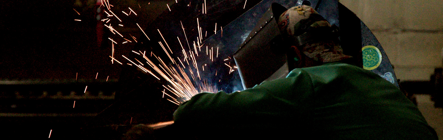 Skilled welder fabricating mechanical piping for commercial HVAC construction at Herman Goldner Co., Inc. in Philadelphia.