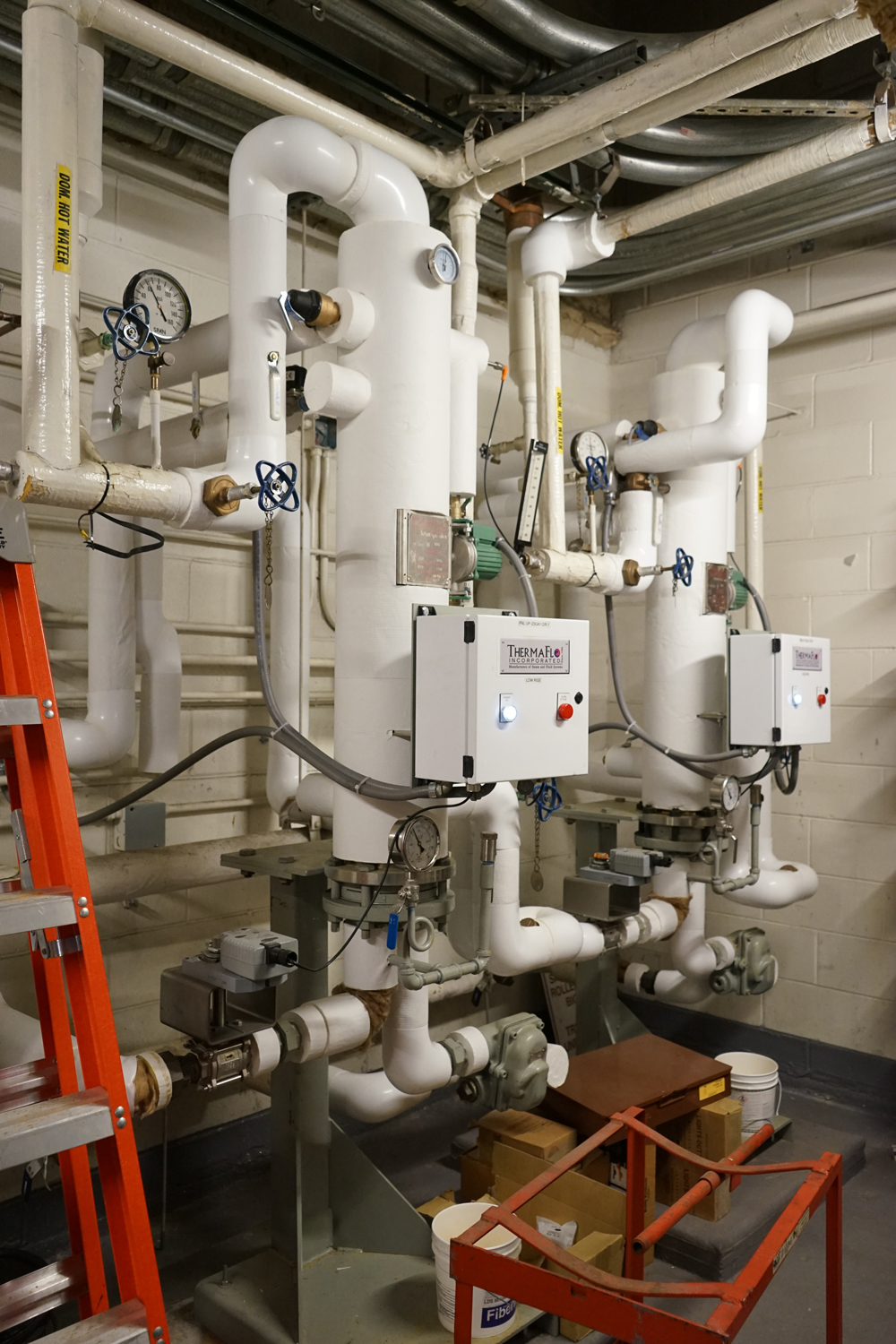 Commercial plumbing system installation by Herman Goldner Co., Inc. featuring water heaters, valves, and control systems for industrial buildings.