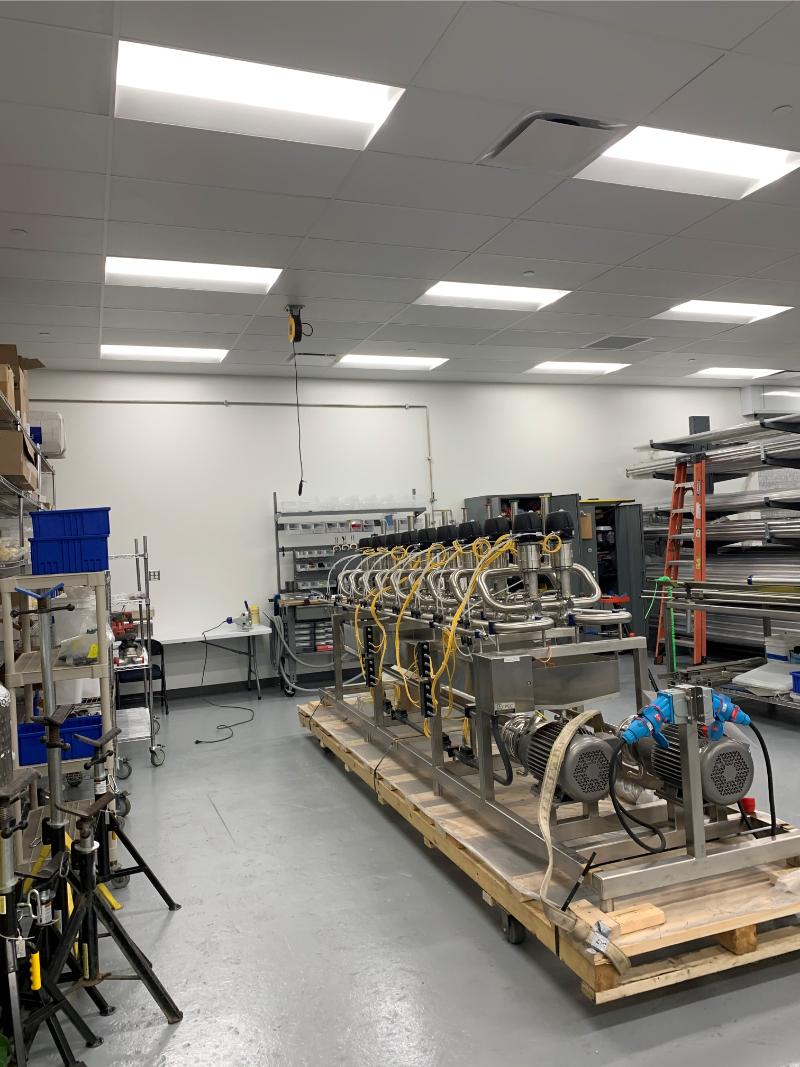Prefabricated stainless steel process skid assembly on workshop floor by Herman Goldner Co., Inc., designed for pharmaceutical and industrial piping systems.