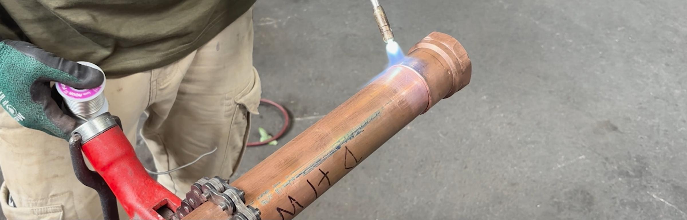 Herman Goldner Co., Inc. plumber soldering copper pipe during commercial plumbing system installation and repair service.
